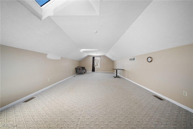 bonus room with vaulted ceiling with skylight, a textured ceiling, and carpet flooring