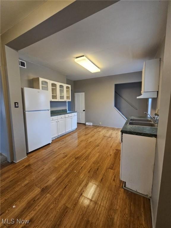 kitchen featuring hardwood / wood-style floors, sink, white fridge, and white cabinets