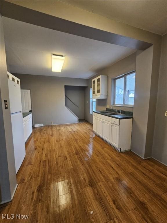 kitchen featuring wood-type flooring, white fridge, sink, and white cabinets