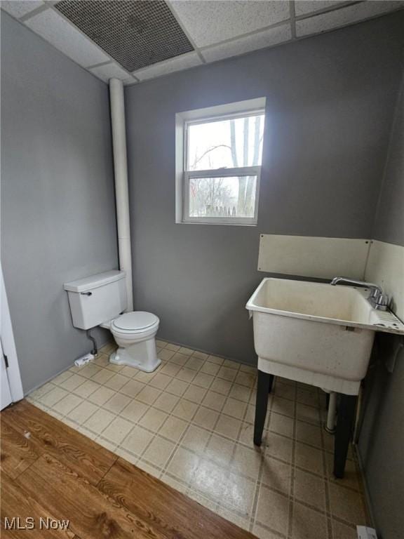 bathroom with a drop ceiling, tile patterned flooring, and toilet