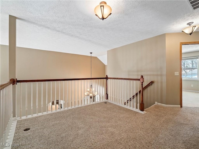 carpeted spare room featuring lofted ceiling, a notable chandelier, and a textured ceiling