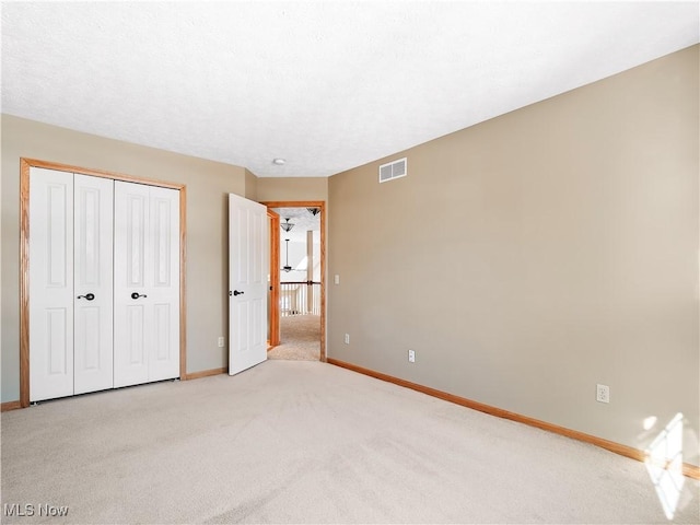 unfurnished bedroom featuring light carpet and a closet