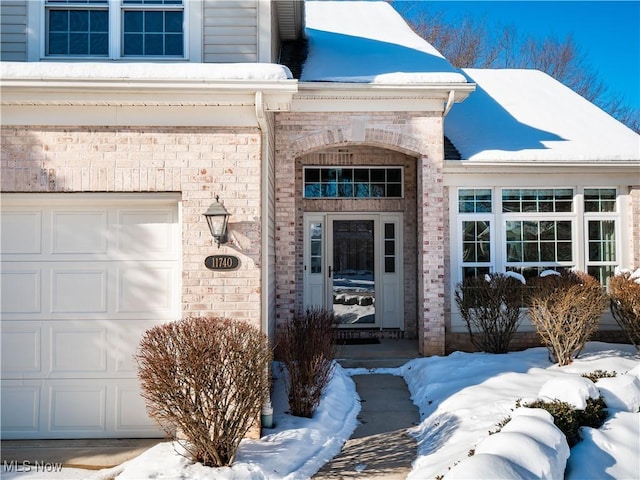 snow covered property entrance with a garage