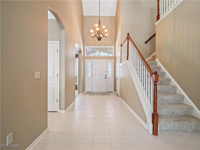 entryway featuring an inviting chandelier, light tile patterned flooring, and a high ceiling