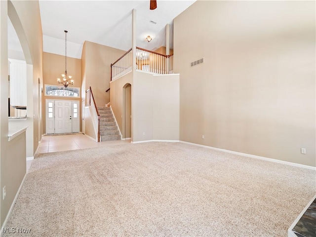 foyer entrance featuring an inviting chandelier, light colored carpet, and high vaulted ceiling