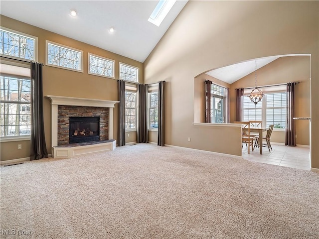 unfurnished living room featuring an inviting chandelier, light carpet, a fireplace, and high vaulted ceiling