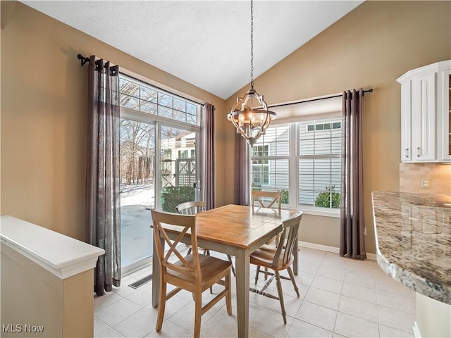 tiled dining room featuring lofted ceiling, a textured ceiling, and a notable chandelier