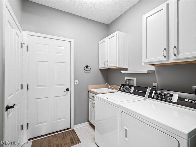 laundry area featuring sink, cabinets, a textured ceiling, light tile patterned floors, and washing machine and dryer