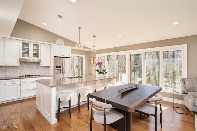 kitchen with a breakfast bar, pendant lighting, an island with sink, sink, and stainless steel appliances