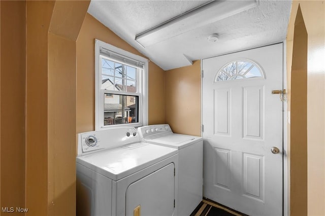 washroom with a wealth of natural light, washing machine and clothes dryer, and a textured ceiling