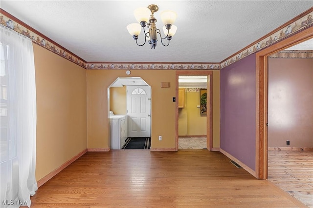 interior space with separate washer and dryer, a notable chandelier, light hardwood / wood-style floors, and a textured ceiling