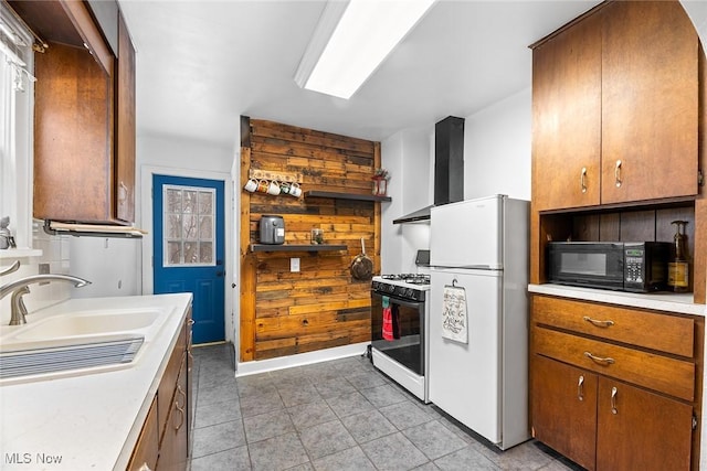 kitchen with sink, white appliances, light tile patterned floors, and wall chimney exhaust hood