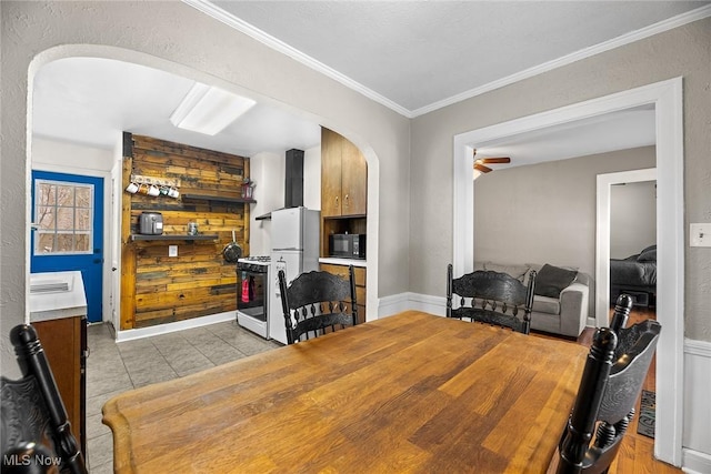 tiled dining space with crown molding and ceiling fan