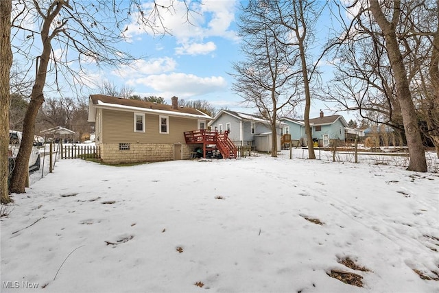 snow covered back of property with a wooden deck