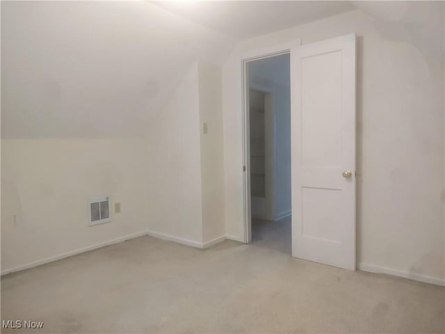 additional living space with light colored carpet and vaulted ceiling