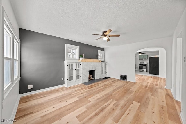 unfurnished living room with light hardwood / wood-style flooring, a brick fireplace, and plenty of natural light