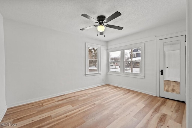 unfurnished room with ceiling fan, light hardwood / wood-style flooring, and a textured ceiling