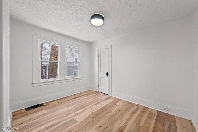 spare room featuring light hardwood / wood-style floors and a textured ceiling