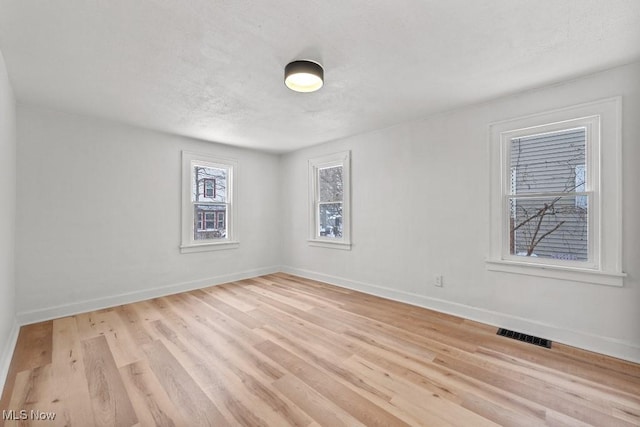 unfurnished room featuring light hardwood / wood-style floors and a textured ceiling