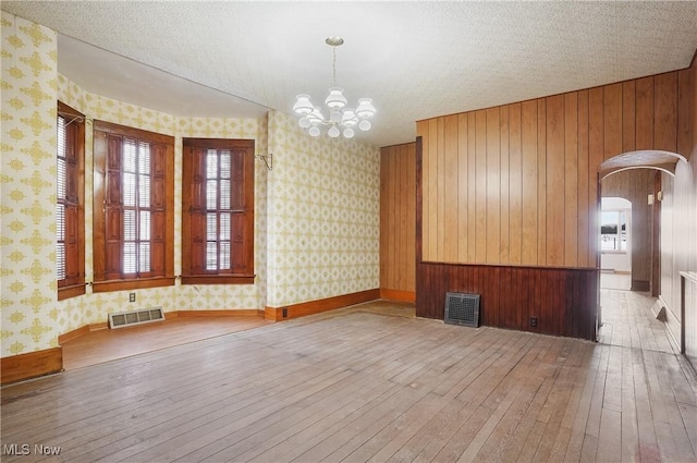 unfurnished room featuring hardwood / wood-style flooring, a notable chandelier, and a textured ceiling