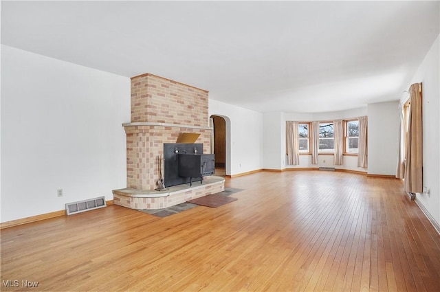 unfurnished living room with a wood stove and light wood-type flooring