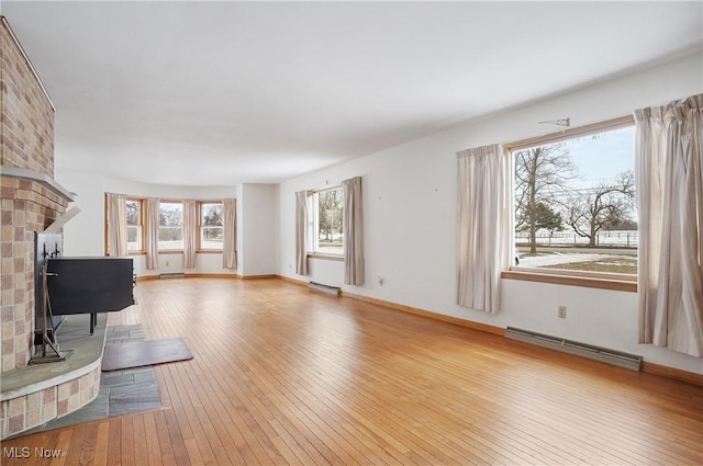 living room with a baseboard heating unit and light hardwood / wood-style flooring