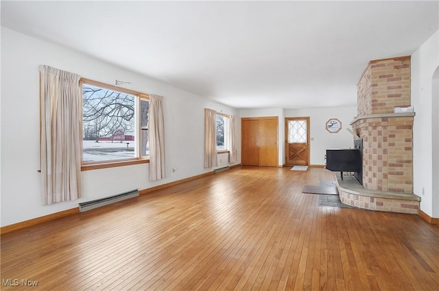 unfurnished living room featuring baseboard heating and light hardwood / wood-style floors