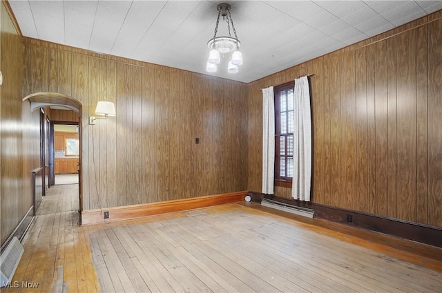 empty room featuring a chandelier and light wood-type flooring