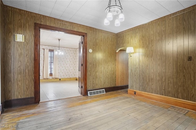 unfurnished room featuring a notable chandelier and light hardwood / wood-style floors