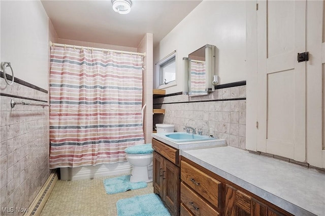 full bathroom with a baseboard radiator, tile walls, vanity, toilet, and tile patterned floors