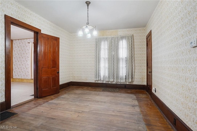 spare room featuring hardwood / wood-style flooring and a chandelier