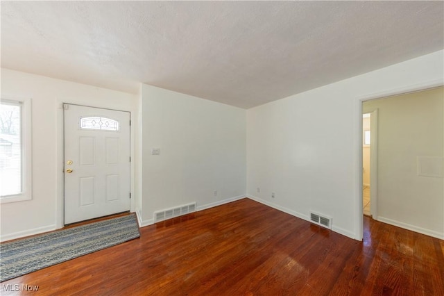 foyer entrance with dark hardwood / wood-style floors and a textured ceiling