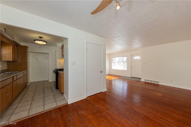 kitchen with ceiling fan, sink, black range with gas stovetop, and light hardwood / wood-style floors