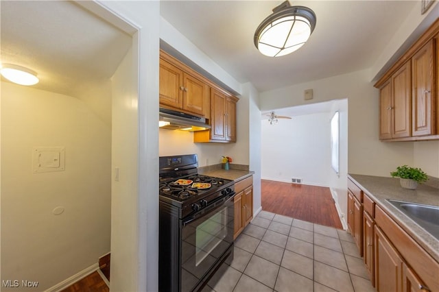 kitchen featuring black range with gas cooktop, sink, and light tile patterned floors