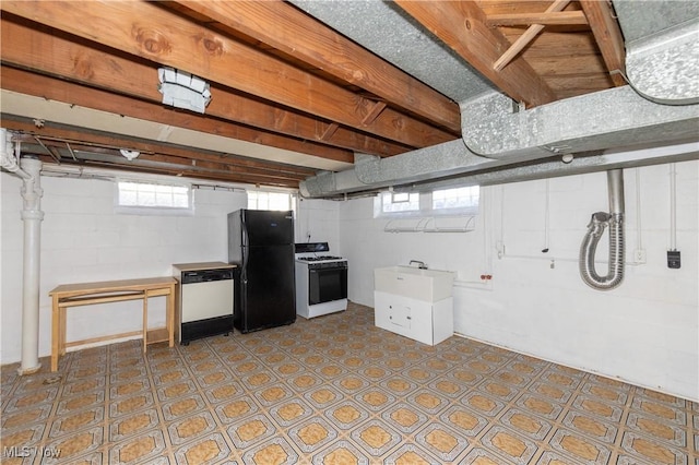 basement featuring a healthy amount of sunlight, black refrigerator, and sink