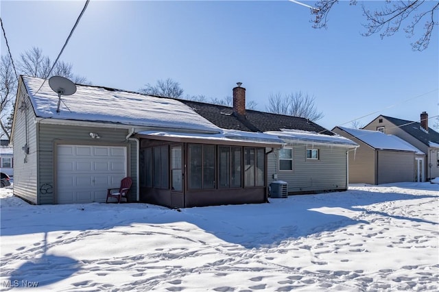 snow covered property with a sunroom and central air condition unit