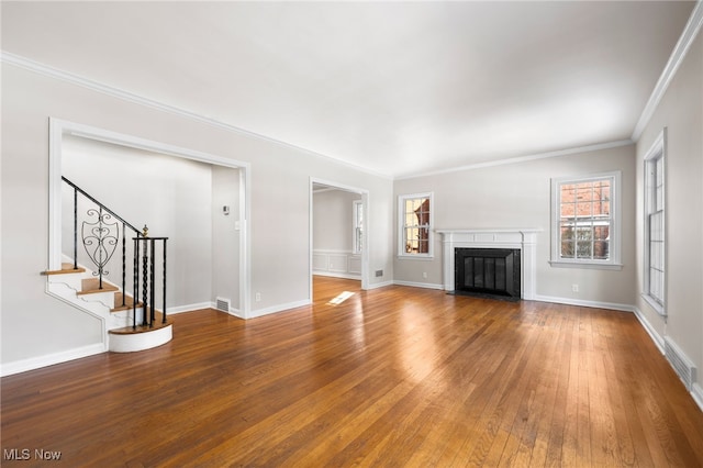 unfurnished living room with hardwood / wood-style flooring, ornamental molding, and a healthy amount of sunlight