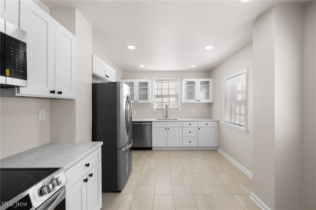 kitchen with light stone counters, sink, white cabinets, and appliances with stainless steel finishes