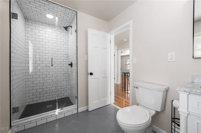 bathroom featuring vanity, toilet, tile patterned floors, and a shower with shower door