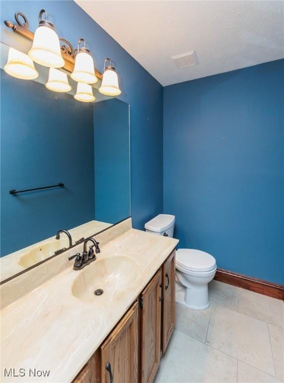 bathroom with vanity, toilet, tile patterned flooring, and a notable chandelier