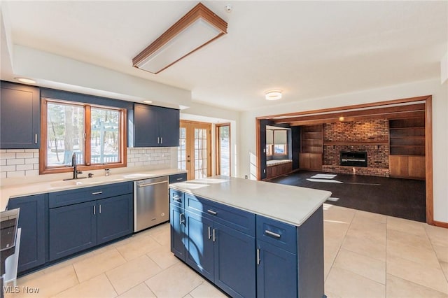 kitchen featuring blue cabinetry, stainless steel dishwasher, sink, and a kitchen island