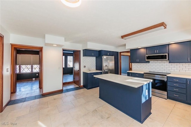 kitchen featuring light tile patterned floors, appliances with stainless steel finishes, a kitchen island, tasteful backsplash, and blue cabinets