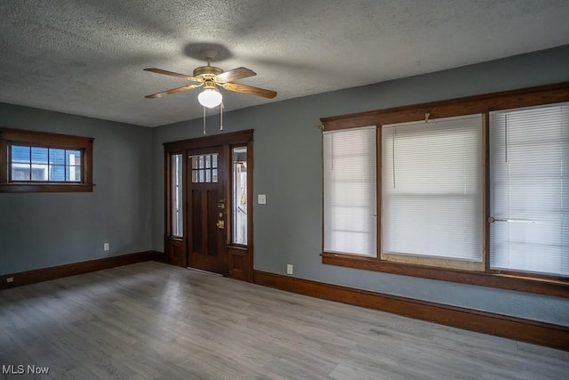 foyer entrance with ceiling fan, wood-type flooring, and a textured ceiling