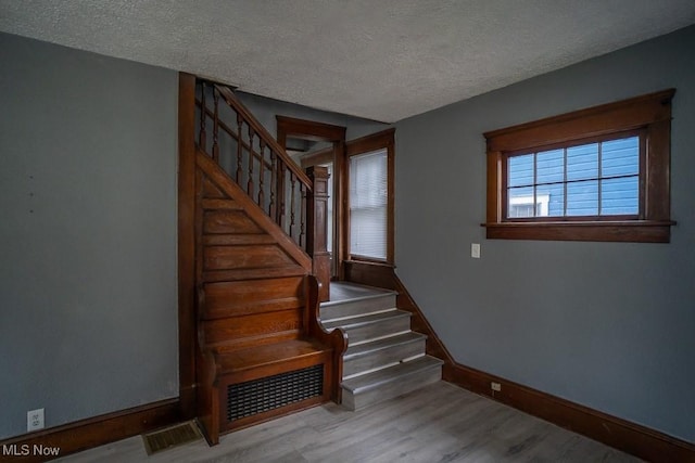 stairway featuring wood-type flooring and a textured ceiling