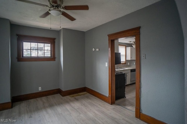 empty room featuring ceiling fan, light hardwood / wood-style floors, and a textured ceiling