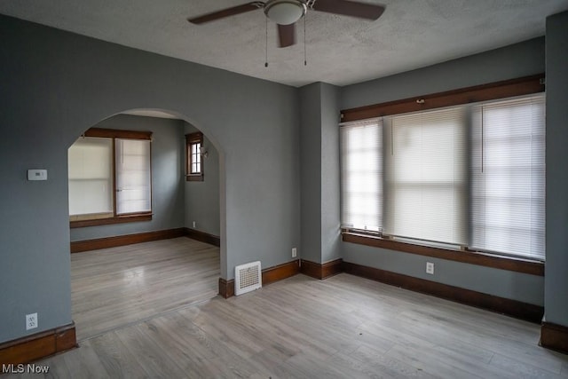 unfurnished room featuring ceiling fan, light hardwood / wood-style floors, and a textured ceiling