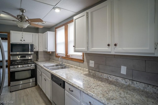 kitchen featuring sink, backsplash, stainless steel appliances, and white cabinets