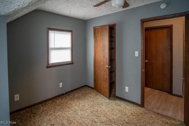 unfurnished bedroom with vaulted ceiling, light carpet, ceiling fan, and a textured ceiling