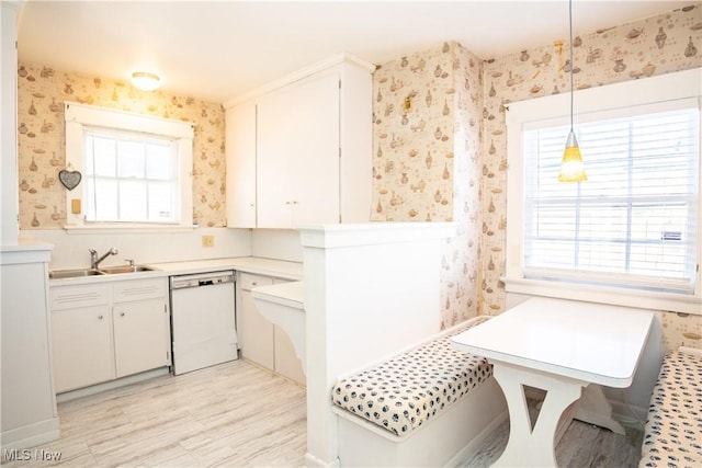 kitchen featuring sink, white cabinetry, plenty of natural light, white dishwasher, and pendant lighting