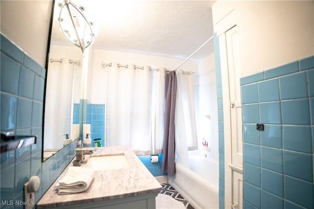 bathroom with shower / bathtub combination with curtain, vanity, and tile walls